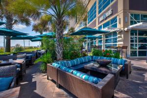 a patio with a couch and tables and umbrellas at Hilton Garden Inn Virginia Beach Oceanfront in Virginia Beach