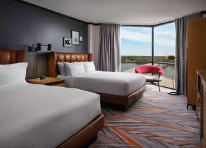 a hotel room with two beds and a balcony at The Landing at Hampton Marina, Tapestry Collection by Hilton in Hampton