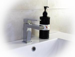a bathroom sink with a soap dispenser on it at Mau Beach House in Lido di Ostia +21 photos