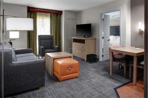 um quarto de hotel com um sofá, uma secretária e uma televisão em Homewood Suites by Hilton Richmond - West End / Innsbrook em Broad Meadows