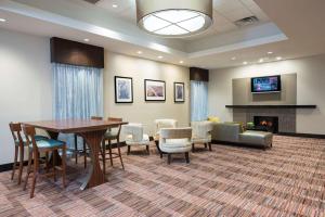 una sala de espera con mesa, sillas y chimenea en DoubleTree by Hilton Hotel Grand Rapids Airport, en Grand Rapids