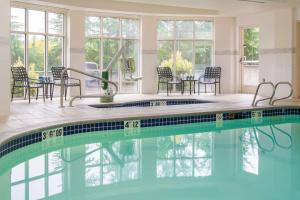 uma piscina com cadeiras e mesas numa casa em Hilton Garden Inn Portland Lake Oswego em Lake Oswego