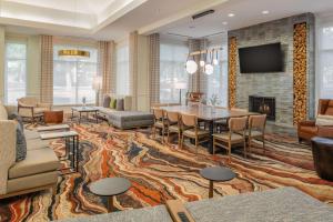 a living room with a table and chairs and a fireplace at Hilton Garden Inn Portland Lake Oswego in Lake Oswego
