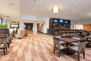 大急流城DoubleTree by Hilton Hotel Grand Rapids Airport的有桌椅和酒吧的餐厅