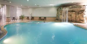 una gran piscina con cascada en una habitación de hotel en Embassy Suites by Hilton Detroit - Livonia/Novi, en Livonia