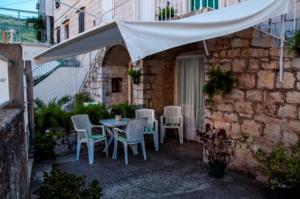 a patio with a table and chairs under a white umbrella at Marina Rooms in Komiža
