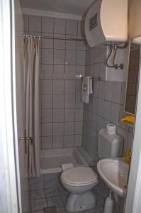 a bathroom with a toilet and a tub and a sink at Marina Rooms in Komiža