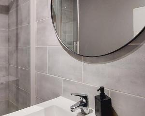 a bathroom with a sink and a round mirror at ArtGrey * Idéal Pro * Roanne Secteur Gare et rue piétonnes in Roanne