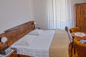 a bedroom with a bed with a wooden headboard and a table at Marina Rooms in Komiža