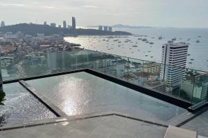 una piscina en la parte superior de un edificio con vistas al agua en Edge Seaside Luxury Stylish Condo steps away from beach en Pattaya Central