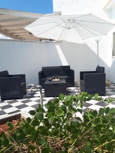 um pátio com mobiliário preto e um guarda-chuva em Villa Rosa con esclusiva vista sul mare em Corsano