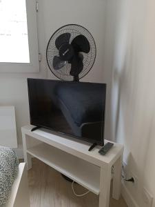 een televisie op een witte tafel met een ventilator bij Le Petit Bonald- studio Universités Lyon 2 et 3 in Lyon