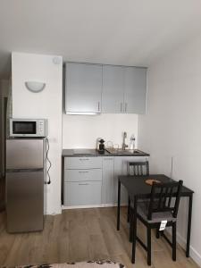 eine Küche mit weißen Schränken, einem Tisch und einer Mikrowelle in der Unterkunft Le Petit Bonald- studio Universités Lyon 2 et 3 in Lyon