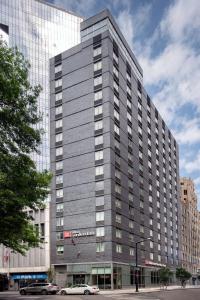 un gran edificio gris con coches estacionados frente a él en Hilton Garden Inn Long Island City en Queens