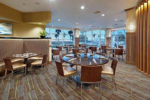 布里斯班DoubleTree by Hilton San Francisco Airport North Bayfront的有桌椅和窗户的餐厅