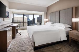 um quarto de hotel com uma grande cama branca e uma secretária em Hilton Seattle em Seattle