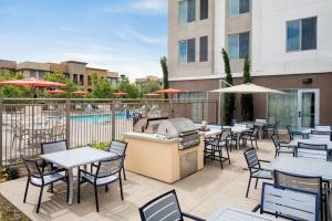 un patio al aire libre con mesas, sillas y una parrilla en Homewood Suites by Hilton Aliso Viejo Laguna Beach en Aliso Viejo