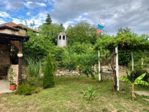 um jardim com uma bandeira e uma parede de pedra em Guest House Devetaki em Devetaki