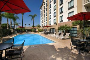 a swimming pool with tables and chairs and a hotel at Hampton Inn & Suites Anaheim Garden Grove in Anaheim