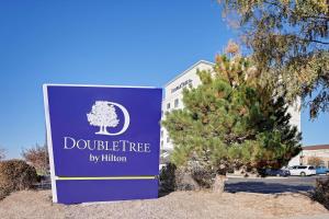 DoubleTree by Hilton Denver International Airport, CO في دنفر: لافته امام مبنى عليه شجرة