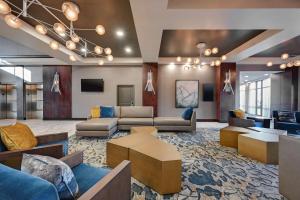 DoubleTree by Hilton Denver International Airport, CO في دنفر: غرفة معيشة كبيرة مع كنب وطاولات