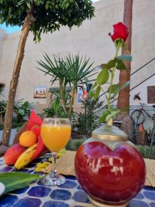 un tavolo con un bicchiere di succo d'arancia e frutta di Riad 4 jardins a Marrakech