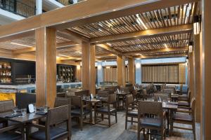 un restaurant avec des tables et des chaises en bois ainsi qu'un bar dans l'établissement Embassy Suites by Hilton Austin Central, à Austin