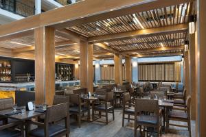 a restaurant with wooden tables and chairs and a bar at Embassy Suites by Hilton Austin Central in Austin