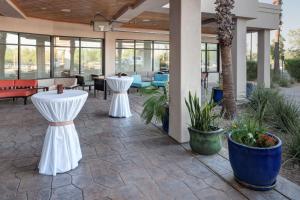 a patio with two white tables and potted plants at Hilton Garden Inn Tucson Airport in Tucson