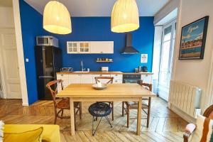 une cuisine avec une table en bois et un mur bleu dans l'établissement Charmant cocon lyonnais Sathonay-Terreaux, à Lyon