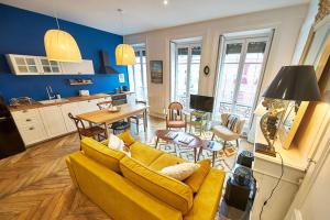 a living room with a yellow couch and a kitchen at Charmant cocon lyonnais Sathonay-Terreaux in Lyon