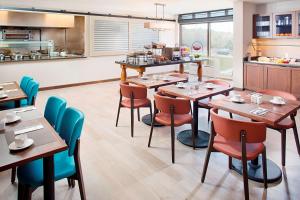 a restaurant with wooden tables and chairs and a kitchen at Hilton Garden Inn Providence in Providence