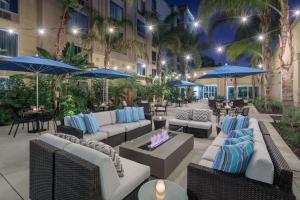 a patio with couches and tables and blue umbrellas at DoubleTree by Hilton Los Angeles/Commerce in Commerce