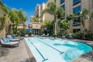una piscina en un hotel con sillas y palmeras en DoubleTree by Hilton Los Angeles/Commerce en Commerce