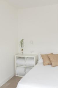 a white bed with a white night stand next to it at Agroturismo Montefrío in Urnieta