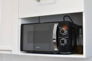 a black microwave sitting on a shelf in a kitchen at Le Jean Moulin - Bords de Saône in Caluire-et-Cuire