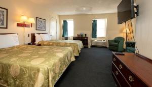a hotel room with two beds and a flat screen tv at Country Squire inn and suites in Coshocton