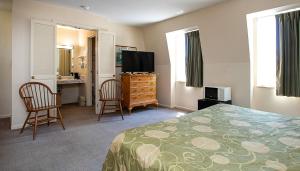 a bedroom with a bed and a desk and a television at Country Squire inn and suites in Coshocton
