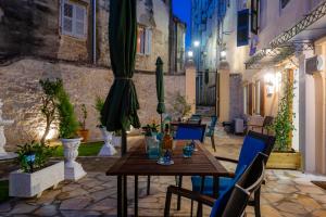a patio with a wooden table and chairs and an umbrella at Volto Suites in Corfu Town