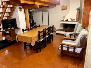 uma sala de jantar com mesa e cadeiras e uma televisão em Villetta Porto Pino 30 mt dalla spiaggia em Porto Pino