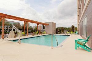 a swimming pool with a green chair next to a building at Home2 Suites By Hilton Orlando South Park in Orlando