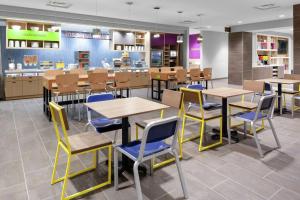 a restaurant with tables and chairs in a cafeteria at Home2 Suites By Hilton Orlando South Park in Orlando