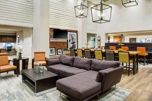 Hampton Inn & Suites Pittsburg Kansas Crossing في بيتسبورغ: غرفة معيشة مع أريكة وغرفة طعام