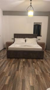 a bed in a bedroom with a wooden floor at N’Kanu in Rrëshen