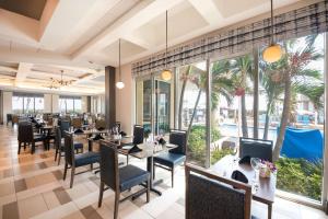 a restaurant with tables and chairs and large windows at Hilton Melbourne Beach Oceanfront in Melbourne