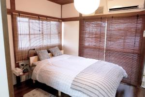 a bedroom with a bed and two large windows at 夢の舎 吉祥寺 Yumenoya Kichijoji in Kichijōji