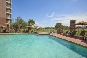 una piscina en un complejo con sillas y sombrillas en Embassy Suites by Hilton Phoenix Scottsdale en Phoenix