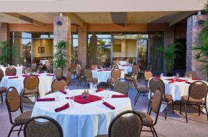 a dining room with white tables and chairs at Embassy Suites by Hilton Phoenix Scottsdale in Phoenix
