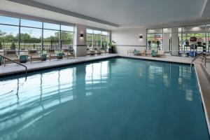 a swimming pool in a hotel with tables and chairs at Homewood Suites By Hilton Teaneck Glenpointe in Teaneck