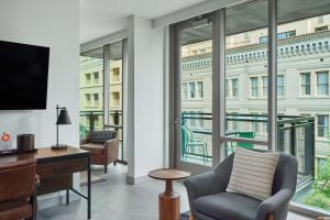 sala de estar con silla, escritorio y ventanas en Canopy By Hilton San Antonio Riverwalk, en San Antonio